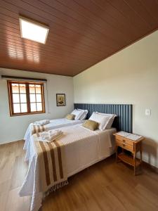 um quarto com 2 camas e um tecto de madeira em Chalé Três - Casa de temporada em Tiradentes em Tiradentes