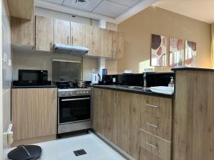 a kitchen with wooden cabinets and a stove top oven at Continental Tower - Vigor Vacation Homes in Dubai