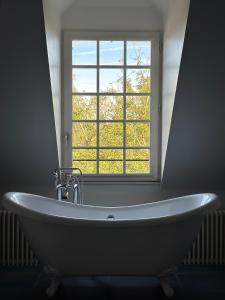 a white bath tub in front of a window at Le Prieuré sur Seine in Marnay-sur-Seine