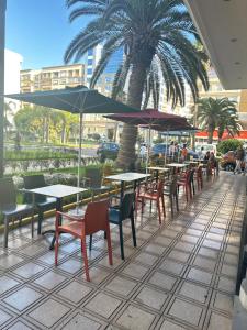 een patio met tafels en stoelen en een palmboom bij App à côté du parc et corniche in Mohammedia