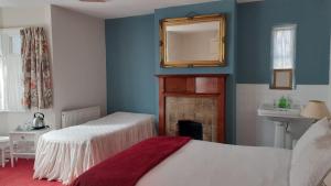 um quarto com 2 camas, um espelho e um lavatório em Kingsway Bed & Breakfast em Broxbourne