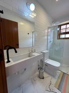 uma casa de banho com um lavatório, um WC e um espelho. em Chalé Três - Casa de temporada em Tiradentes em Tiradentes