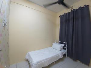 a small room with a bed and a blue curtain at Afya Alya Guesthouse Melaka in Melaka