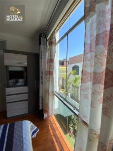 - une chambre avec une grande fenêtre offrant une vue dans l'établissement HOTEL HUARAZ, à Tacna