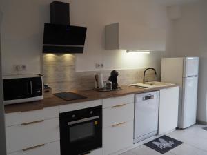 a kitchen with white cabinets and a black appliance at Le Cocon in Millau
