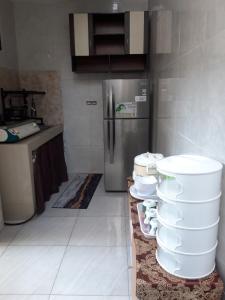 a kitchen with a stack of plates and a refrigerator at Koral Guesthouse in Malang
