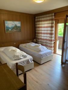 Un dormitorio con dos camas y una mesa. en Hotel Principe, en Selva di Cadore