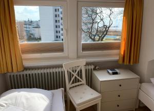 een slaapkamer met een bed en een stoel en 2 ramen bij Gästehaus Windrose Wohnung 6 in Pelzerhaken