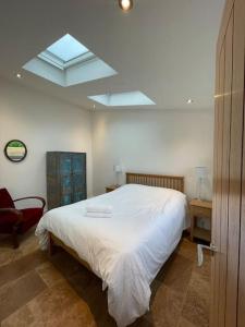 a bedroom with a white bed and a skylight at Tranquil, secluded, rural cottage for two in Beaumaris