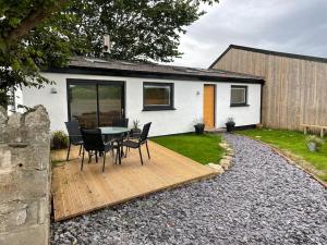 a house with a table and chairs on a wooden deck at Tranquil, secluded, rural cottage for two in Beaumaris