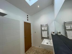 a white bathroom with a sink and a mirror at Tranquil, secluded, rural cottage for two in Beaumaris