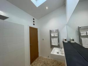 a white bathroom with a sink and a mirror at Tranquil, secluded, rural cottage for two in Beaumaris +24 photos