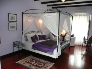 A Dream in Beauty and Tranquility في Almogía: غرفة نوم مع سرير المظلة مع الوسائد الأرجوانية