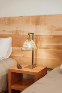 a lamp on a wooden table next to two beds at PURA Hotel in Coihaique
