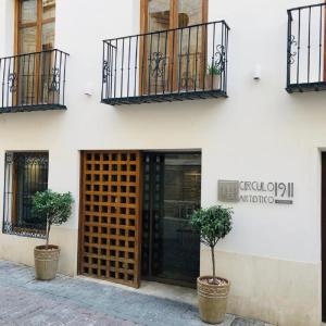 a building with two potted trees in front of a door at Círculo Artístico 1911 Hotel Boutique in Caravaca de la Cruz