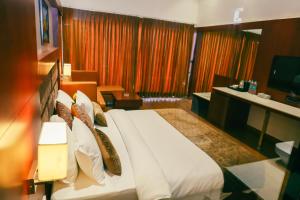 ein Hotelzimmer mit einem großen Bett und einem TV in der Unterkunft Oralia Resort in Velha Goa