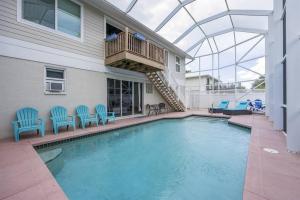 a swimming pool with blue chairs and a balcony at Capri Charm Remodeled Oasis w/ Heated Pool-Kayaks in Naples