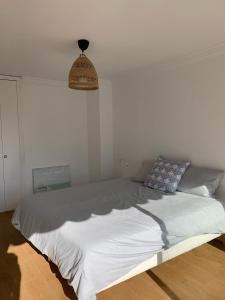 a bed in a bedroom with a white wall at Appartement LUNA - lumineux, vue mer, à 50m de la plage, climatisé et parking inclus in Cagnes-sur-Mer