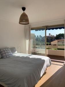 a bedroom with a large bed and a large window at Appartement LUNA - lumineux, vue mer, à 50m de la plage, climatisé et parking inclus in Cagnes-sur-Mer