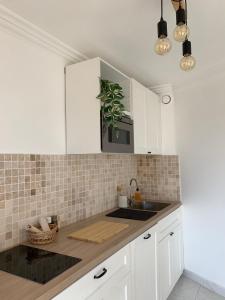 a kitchen with white cabinets and a sink at Appartement LUNA - lumineux, vue mer, à 50m de la plage, climatisé et parking inclus in Cagnes-sur-Mer