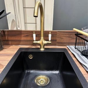 a black sink with a brass faucet in a counter at The Cabin Near Stansted Airport in Little Hallingbury