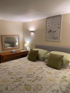 a bedroom with a bed with green pillows and a mirror at Ground Floor Garden Cottage, near Stonehenge in Shrewton