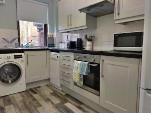 cocina con armarios blancos, lavadora y secadora en amazing apartments: Dorset Place - free parking, en Edimburgo