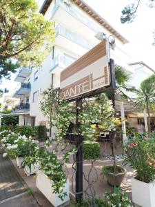 a sign in front of a building with plants at Hotel Dante in Lido di Jesolo