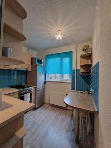 里加的住宿－Iļģuciema Apartment，厨房配有桌子和蓝色窗户。