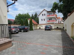 a parking lot with cars parked in front of a building at Jázmin Apartman in Harkány