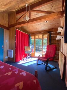 Schlafzimmer mit einem roten Stuhl und roten Vorhängen in der Unterkunft CHALET SAVINES LE LAC in Savines