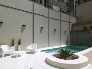 un edificio con piscina, 2 sillas y mesa en Recoleta Uriburu by Ayres en Buenos Aires