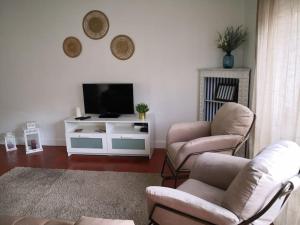 a living room with two chairs and a television at Beach and Surf Lovers in Costa da Caparica