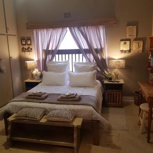 a bedroom with a large bed with pillows and a window at Rubyred Cottage in Bloemfontein