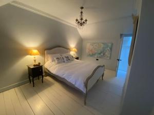 a bedroom with a white bed and a chandelier at Kirkcudbright 3 bed ultra modern brand new in Kirkcudbright