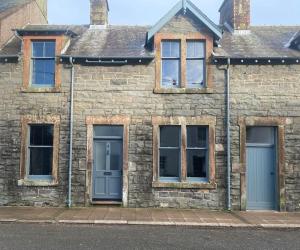 a brick building with three windows and a blue door at Kirkcudbright 3 bed ultra modern brand new in Kirkcudbright