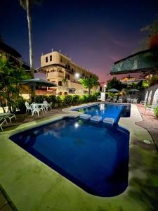 ein großer Pool mit Stühlen und ein Gebäude in der Unterkunft Hotel Villas Ema in Zihuatanejo