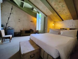 1 dormitorio con 1 cama grande y 1 silla en Casa Baladin camere di Charme e Agronidi dell'Open Garden en Piozzo