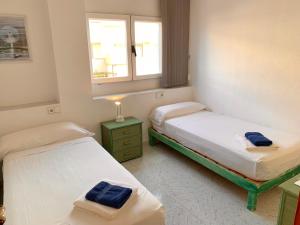 two beds in a small room with a window at APT Borras & Roca Plana, fronte mare in Es Pujols