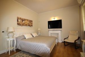1 dormitorio con 1 cama, TV y silla en Stanze Degli Aceri, en Murazzano