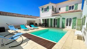a swimming pool in front of a house at Superbe villa d'architecte avec piscine chauffée in Loix