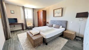a bedroom with a bed and a chair and a television at Superbe villa d'architecte avec piscine chauffée in Loix