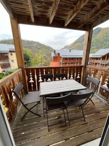 a wooden deck with a table and chairs on it at Joli appartement avec terrasse in Ax-les-Thermes +5 photos