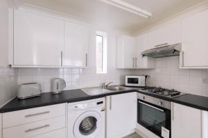 Una cocina blanca con fregadero y lavavajillas. en Amazing 1 Bed Flat with Free Parking, en Croydon