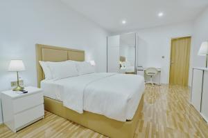 a bedroom with a large white bed and a mirror at Akomadoo Retreat in Kamadhoo