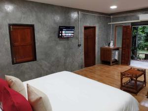 a bedroom with a bed and a tv on the wall at Mind's Homestay มายด์โฮมสเตย์ in Kampong Huaibū