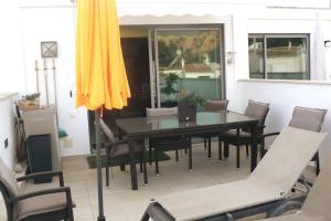 a dining room table with chairs and a yellow umbrella at Magnifique Duplex avec piscine en bord de mer in Olhos de Água