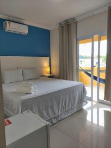 um quarto com uma cama branca e uma parede azul em Pousada Marcos no Guarujá