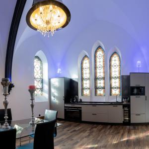 ein Esszimmer mit einem Kronleuchter und zwei Buntglasfenstern in der Unterkunft LA BELL'CHAPELLE in Remiremont