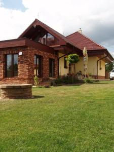 uma casa de tijolos com um relvado verde em frente em Vilka Relax em Podhájska